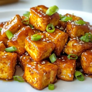 To make this tasty dish, you need some simple ingredients. Here’s what you will use: - 14 oz (400g) firm tofu, pressed and cubed - 3 tablespoons honey (or agave nectar for vegan) - 2 tablespoons soy sauce - 2 cloves garlic, minced - 1 tablespoon rice vinegar - 1 tablespoon cornstarch - 1 teaspoon sesame oil - 1/2 teaspoon red pepper flakes (optional) - 2 green onions, sliced for garnish - Sesame seeds for garnish Each ingredient adds a unique flavor. The tofu gives protein, while honey and soy sauce bring sweetness and saltiness. Garlic adds a wonderful aroma, and sesame oil gives a nice nutty taste. You can swap some items if you need to. If you want a vegan option, use agave nectar instead of honey. For gluten-free, use tamari instead of soy sauce. You can also change the vinegar. Use apple cider vinegar if you don't have rice vinegar. If you like a spicy kick, you can add more red pepper flakes. If you want a milder taste, leave them out. Garnishes can make your dish more fun. I recommend using: - Sliced green onions - Sesame seeds These add color and crunch. You can also try adding chopped cilantro or crushed peanuts for a different twist. {{ingredient_image_1}} First, choose firm tofu for the best texture. Press the tofu for at least 30 minutes. This step removes extra moisture. You can use a clean kitchen towel or paper towels. Place a weight on top to help press it down. After pressing, cut the tofu into bite-sized cubes. This size helps it cook evenly and get crispy. Next, let’s make the marinade. In a bowl, whisk together these ingredients: - 3 tablespoons honey (or agave nectar for vegan) - 2 tablespoons soy sauce - 2 cloves garlic, minced - 1 tablespoon rice vinegar - 1 teaspoon sesame oil - 1/2 teaspoon red pepper flakes (optional) Mix until everything combines well. The honey adds sweetness, and the garlic gives bold flavor. Now, it’s time to marinate the tofu. Place the cubed tofu in the bowl with the marinade. Gently toss to coat all sides. Let it marinate for 15-30 minutes. This wait helps the tofu soak up the flavors. After marinating, sprinkle 1 tablespoon of cornstarch over the tofu. Toss it again to coat each piece. This step is key for a crispy outside. Preheat your air fryer to 375°F (190°C). Place the tofu cubes in a single layer in the basket. If you have too much, cook in batches. Air fry for 15-20 minutes. Shake the basket halfway through to ensure even cooking. The tofu should turn golden brown and crispy. Once cooked, remove the tofu from the air fryer. Add it back to the bowl with any leftover marinade. Toss gently to glaze the crispy tofu. Your air fryer honey garlic tofu is now ready to serve! 1. Press the Tofu: Always press tofu for at least 30 minutes. This step removes extra moisture. 2. Use Firm Tofu: Choose firm or extra-firm tofu. It holds its shape and gets crispier. 3. Cornstarch Coating: Coat the marinated tofu with cornstarch. This creates a crunchy outer layer. 4. Single Layer: Place tofu cubes in a single layer in the air fryer. This ensures even cooking. 1. Marinate Time: Let the tofu sit in the marinade for 15-30 minutes. Longer time means more flavor. 2. Gently Toss: Toss tofu gently when marinating. This helps to coat each piece without breaking it. 3. Use Fresh Garlic: Always use fresh minced garlic. It adds a strong, rich taste to the dish. 4. Adjust Sweetness: Feel free to adjust honey or agave nectar. Customize the sweetness to your taste. 1. Not Crispy Enough: If the tofu isn’t crispy, check the cornstarch coating. Make sure it’s even. 2. Burnt Tofu: If tofu burns, lower the air fryer temperature. Cooking at 350°F (175°C) can help. 3. Flavorless Tofu: If tofu lacks flavor, marinate for a longer time. You can also add more soy sauce. 4. Sticky Tofu: If tofu sticks to the basket, use a little spray oil. This helps prevent sticking during cooking. Pro Tips Press the Tofu: Ensure the tofu is pressed thoroughly to remove excess moisture, which allows it to absorb the marinade better and achieve a crispier texture when cooked. Adjust Sweetness: If you prefer your tofu on the sweeter side, feel free to add a bit more honey or agave nectar to the marinade for extra flavor. Even Cooking: Arrange the tofu in a single layer in the air fryer to ensure even cooking and crispiness. Avoid overcrowding the basket. Customize the Marinade: Experiment with additional ingredients like ginger or lime juice in the marinade for a unique twist on the flavor profile. {{image_2}} For a vegan twist on honey garlic tofu, simply swap honey for agave nectar. This change keeps the sweet flavor while aligning with vegan diets. Agave nectar has a similar taste and works great in marinades. You can also use maple syrup as a substitute. It adds a unique flavor that many enjoy. You can play with different sauces to change the flavor. Try using teriyaki sauce for a sweet and savory kick. Another option is hoisin sauce, which gives a rich taste. For a spicy touch, add sriracha or chili garlic sauce. Mixing these sauces with the basic marinade can create new flavors. Don't be afraid to experiment! Pair your honey garlic tofu with tasty sides. Serve it over jasmine rice or quinoa for a filling meal. You can also add steamed broccoli or stir-fried veggies for extra color and nutrition. A fresh salad with a light dressing makes a great side too. You can even wrap it in lettuce leaves for a fun, hand-held meal! To store leftover honey garlic tofu, let it cool first. Place the tofu in an airtight container. This helps keep it fresh. You can keep it in the fridge for up to three days. Make sure the lid is tight to avoid moisture loss. To reheat your tofu, use an air fryer for the best results. Preheat the air fryer to 350°F (175°C). Place the tofu in the basket and heat for about 5 to 7 minutes. This way, it stays crispy. You can also use a microwave. Just warm it for 1 to 2 minutes. But be aware, it will lose some crispiness in the microwave. Yes, you can freeze honey garlic tofu. First, make sure it's fully cooled. Then, place it in a freezer-safe container or bag. Remove as much air as you can. It can last up to three months in the freezer. When you want to use it, thaw it in the fridge overnight before reheating. Yes, you can use different kinds of tofu. Firm and extra-firm tofu work best for this recipe. These types hold their shape and crisp up nicely. Soft or silken tofu is not great for air frying. They break apart easily. If you want a different texture, try marinating tempeh instead. It also absorbs flavors well and cooks nicely in an air fryer. To make this dish gluten-free, use tamari instead of regular soy sauce. Tamari is a gluten-free soy sauce. Check the honey or agave nectar labels too. Most brands are gluten-free, but it's good to confirm. Avoid using other sauces that may contain gluten. This way, you ensure a tasty dish for everyone! For firm or extra-firm tofu, set your air fryer to 375°F (190°C). This temperature crisps up the tofu well. If you use softer tofu, reduce the cooking time to avoid mushiness. Start with 10-12 minutes and check for doneness. Always shake the basket halfway through cooking for even crisping, no matter the type of tofu. This blog post covered how to make Air Fryer Honey Garlic Tofu. We explored the main ingredients, substitutions, and tasty garnishes. You learned step-by-step instructions for preparing tofu, making the marinade, and getting that perfect air-fried finish. I also shared tips for crispy tofu and ways to enjoy variations or side dishes. In the end, whether you’re a tofu fan or new to it, this dish is easy and tasty. Enjoy cooking and get creative with your flavors!